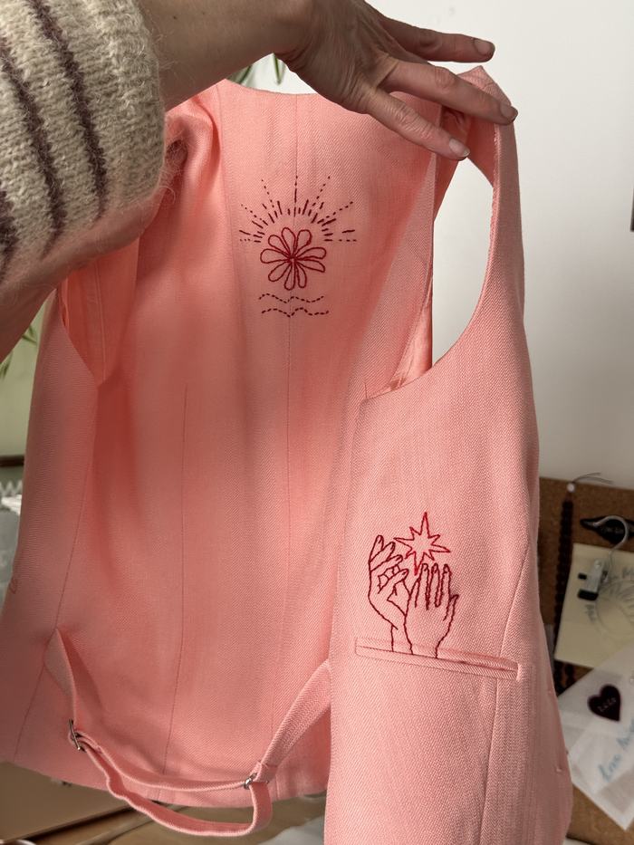 Hand-embroidered garment lining with a sunburst flower and a hand catching a star